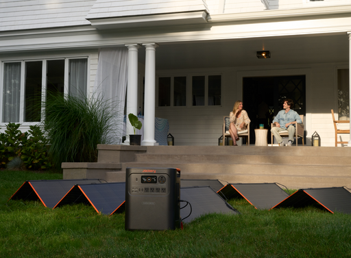 Jackery HomePower 3600 Plus Solar Generator + Choose Your Custom Package on grass with people sitting on a deck in the background