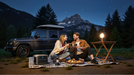 Anker SOLIX C1000 Gen2 1,024Wh | 2,000W Solar Generator + Choose Your Custom Package Couple enjoying a picnic by a car in a mountainous area at night.