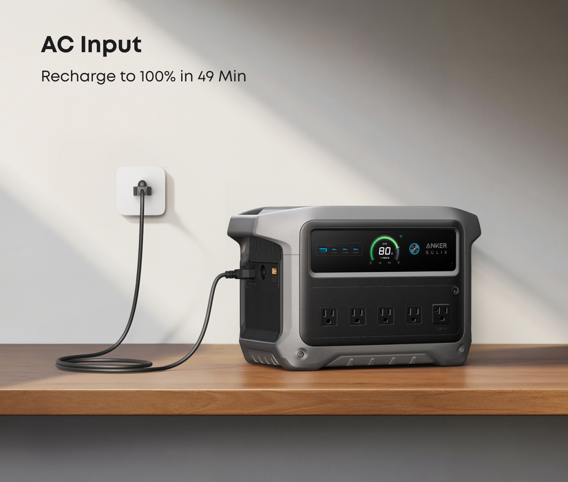 Anker SOLIX C1000 Gen2 1,024Wh | 2,000W Solar Generator + Choose Your Custom Package on a white background with AC input on a wooden surface, charging cable plugged in.