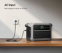 Anker SOLIX C1000 Gen2 1,024Wh | 2,000W Solar Generator + Choose Your Custom Package on a white background with AC input on a wooden surface, charging cable plugged in.