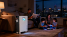 Family in a living room with a pECO-WORTHY PowerMega 314 | 51.2V 314Ah Lithium Battery 16kWh | Bluetooth and WiFi | Active Balance and cityscape view. www.mygeneratorplus.com